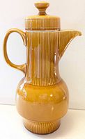 Side view of ribbed ceramic coffee pot with handle and lid