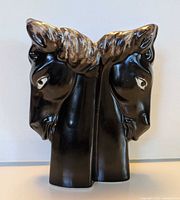Front view showing opposing horse heads and glossy black glaze