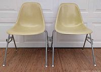 Front view of both yellow fiberglass chairs showing shells and bases