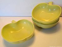 Stack of four yellow apple-shaped bowls showing side profile