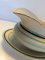Side view of gravy boat on underplate showing color bands and spout profile