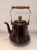 Full view of brown enamel kettle with wood handle and spout