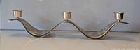 Full view of stainless steel wave candelabra showing three candle cups