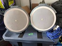 Front view of two round white JBL Control 26CT ceiling speakers on tote