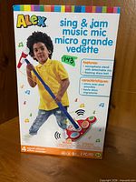 Front of sealed box showing product name, child using microphone and features