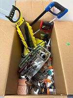 Open cardboard box showing saws, screwdrivers, hardware organizers and small parts