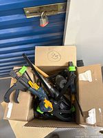 Open cardboard box showing clamps, hand plane, chisel and other tools