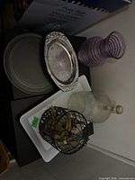 Overall view: purple glass vase, silver tray, grey tray, clear bottle vase, white ceramic tray, wire cage