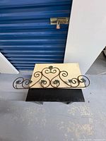 Front view of brown scrolled metal wall rack with green leaf accents and five hooks