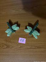 Two green dragonfly-shaped candles displayed on tabletop