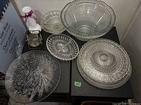 Assorted clear glass bowls and platters, lantern and candle displayed on table