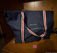 Front view of navy insulated tote showing handles, front zipper pocket