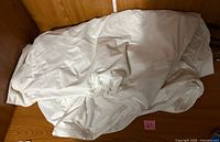 Folded white zippered mattress protector on wooden surface