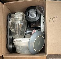 Top view inside box showing blender base, glass pitcher, muffin pan, food container, lid