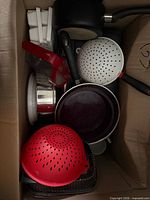 Box interior showing colanders, saucepans, ice cube trays