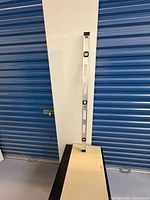 Full view of aluminum spirit level leaning against wall