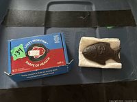 Closed Lucky Iron Fish box beside cast-iron fish on paper towel