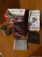 Full lot showing sander, dust canister, box, manual, accessories