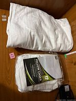 Folded white queen fitted sheet and sealed package of two white Utopia Bedding pillowcases