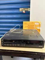Front view of Toshiba VHS VCR showing controls and included manual envelope