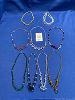 Group shot of eight necklaces and two bracelets on blue background