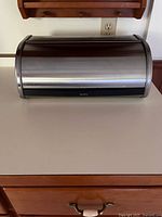 Front view of stainless steel roll-top bread box on counter