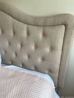 Front view showing tufted beige linen headboard attached to bed
