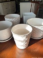 Group shot of five white planters on table