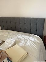 Grey tufted fabric headboard attached to queen bed