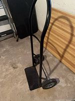 front angled view of black metal hand truck with wheels and toe plate