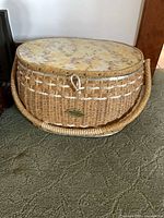 Exterior view of oval wicker sewing basket with floral lid and handle