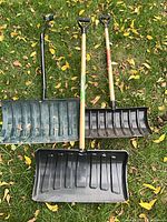 Three snow shovels laid on grass showing full view