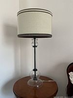 Full view of first lamp showing glass globe base, metal rod, drum shade