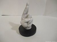 Front view of white hand sculpture on black base