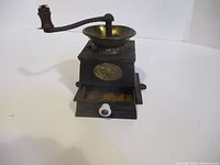 Front view showing cast iron body, brass hopper, crank and drawer