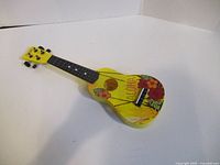 Angled front view of full yellow floral ukulele