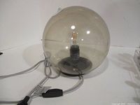 Full view of spherical smoked glass lamp with cord and plug