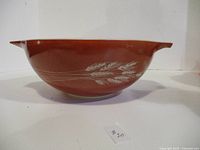 Side view of reddish-brown Pyrex bowl with wheat design