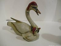 Side view of carved wooden mother and baby duck figurine, hats visible