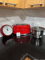 Smeg toaster centered, wall clock left, colander right