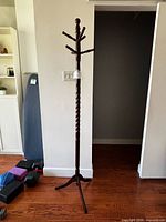 Full view of coat rack showing height, twist post, base, surrounding items for scale