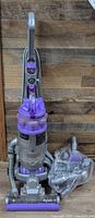 Front view of Dyson upright vacuum with dust bin and accessory bag