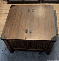 Overhead view of square dark walnut coffee table showing lift-top seam and metal corner brackets