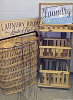 Group shot of wicker hamper, rolling caddy, two laundry signs, metal toilet paper holder