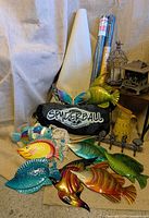 Group shot showing all items including sun shade, landscape fabric rolls, fish plaques, butterfly, pitcher, towel rack, birdcage, table, bag, balcony screening