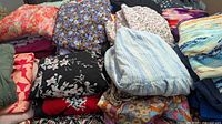 Folded piles of assorted women’s garments showing variety of colours and prints