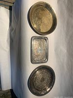 Three silver-tone plates laid out: oval top, rectangular middle, round bottom