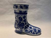 Side view of blue and white porcelain boot vase showing floral design and overall condition