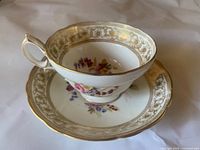 Teacup on saucer showing floral pattern and gold trim