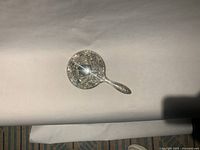 Top view of ornate silver plated hand mirror showing full size and decorative back
